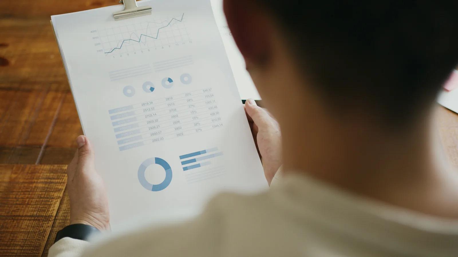 A person reviewing business performance data with charts on a clipboard in an office setting. 6 things nobody tells you about executive summaries checklist
