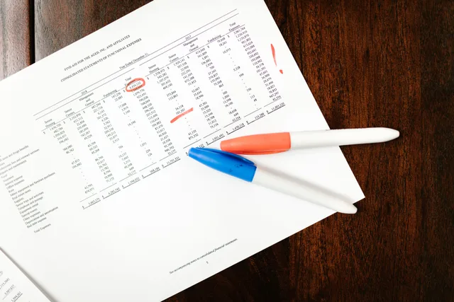 Top view of financial document with red marks and pens on wooden table surface. Executive summary mistakes: what to fix first when time is short
